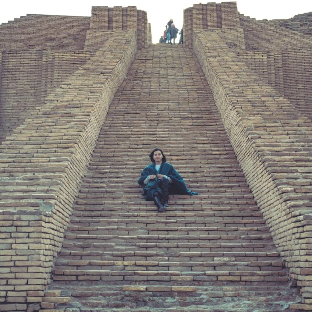 a woman sitting on the access staircase of the ziggurat of ur in iraq