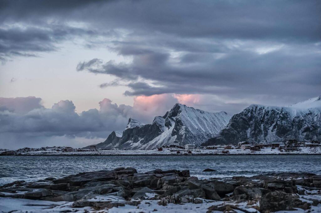 rocky mountain near body of water under cloudy sky
