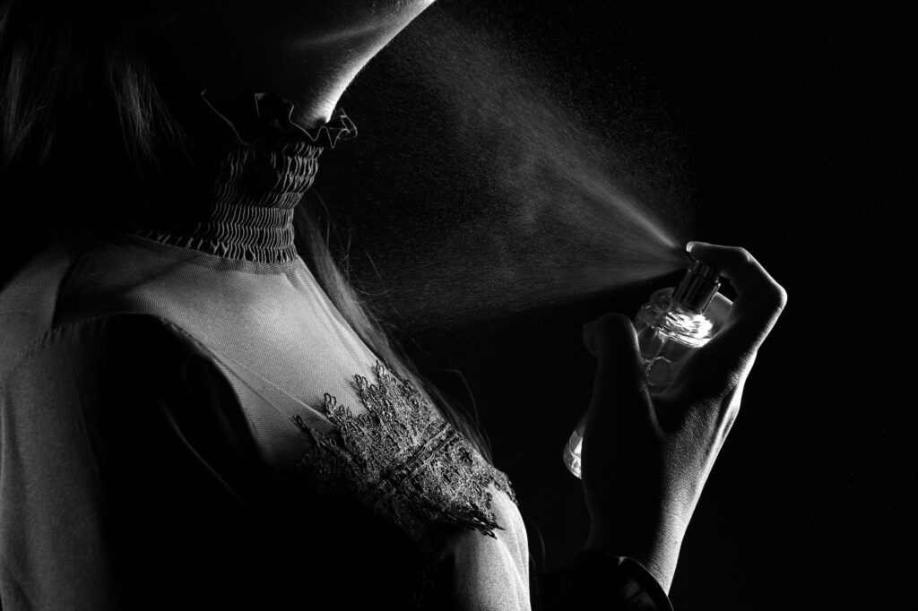 grayscale photo of person spraying perfume